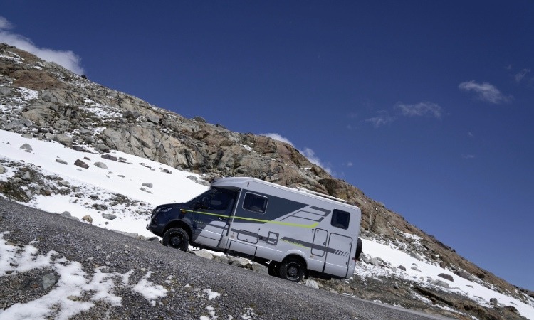 A HYMER ML-T570 Crossover Four Wheel Drive Motorhome being driven up a terrain with snowy mountain