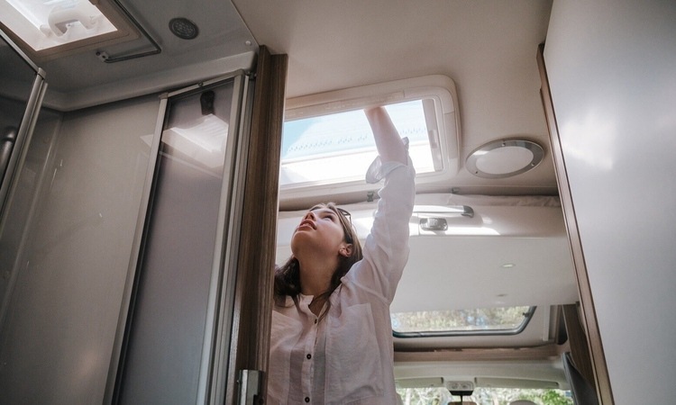 A woman opening up the skylight vent for some air ventilation