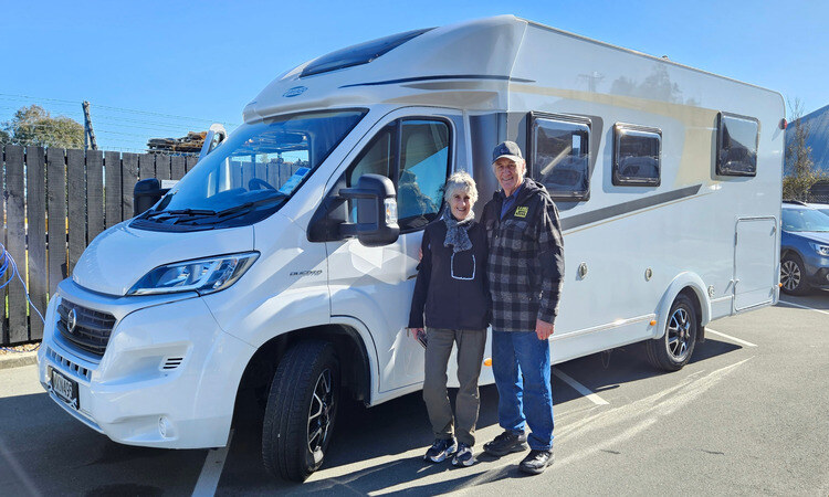 Owners of new motorhome standing beside general exterior