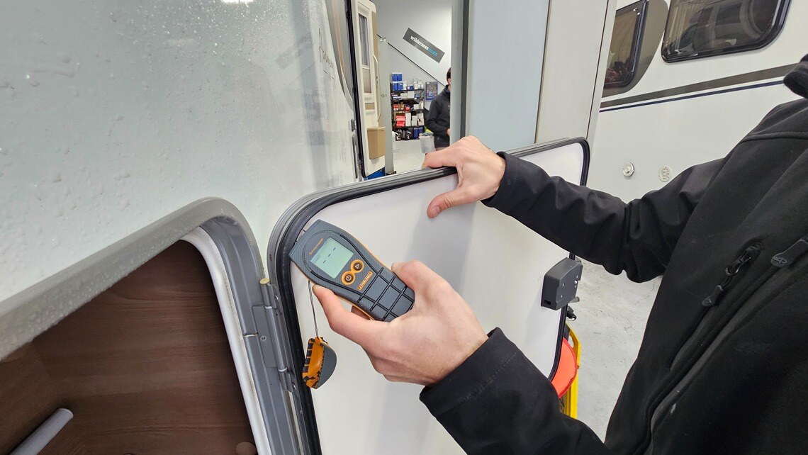 A technician using a moisture detector during a water tightness test