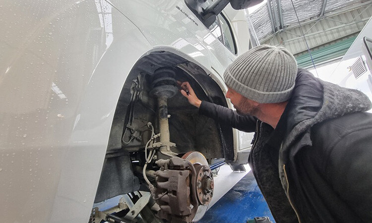 A technician inspecting the suspension of a motorhome